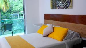 a bedroom with a bed with yellow pillows and a window at Hotel Sama in Montería