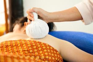 a woman laying on a couch holding a ball of tissue at Lampang River Lodge - SHA certified in Lampang