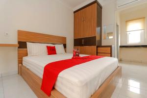 a bedroom with a large bed with a red blanket on it at RedDoorz Plus near Palembang Square Mall in Palembang