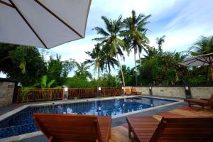 a swimming pool with chairs and an umbrella at Sari Villa Ubud in Ubud