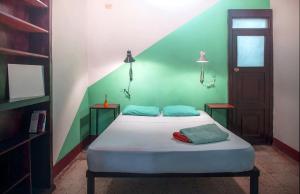 Bett in einem Zimmer mit grüner Wand in der Unterkunft Hostel De Boca en Boca in Granada