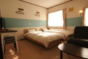Habitación con 2 camas, ventana y silla en Lodge Hahnenkamm en Nozawa Onsen