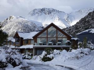 a house with a mountain range and snow covered mountains at Aoraki Mount Cook Alpine Lodge in Mount Cook Village