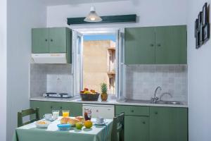 a kitchen with green cabinets and a table with food on it at Golden Sun in Hersonissos