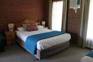 um quarto com uma cama grande numa parede de tijolos em Aristocrat Waurnvale em Geelong