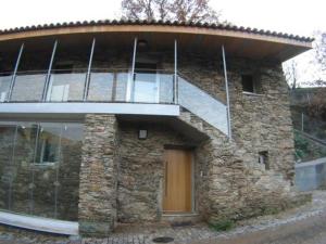 a stone building with a balcony on top of it at Quinta dos Castanheiros - Turismo Rural in Negreda