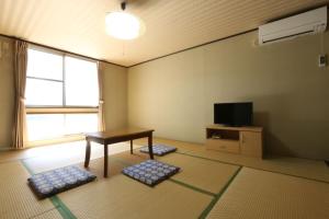 a living room with a table and a television at Business Hotel Amakusa in Yanagi