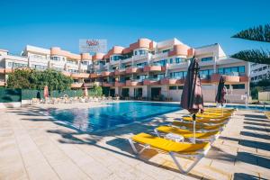 un hotel con sedie e ombrelloni accanto a una piscina di Grand Muthu Forte Da Oura ad Albufeira