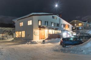 a house with a car parked in the snow at night at Niseko Side 6 in Niseko