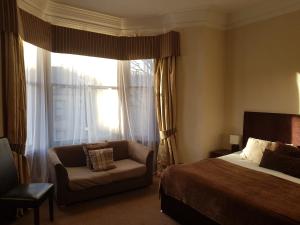 a bedroom with a bed and a chair and a window at Breadalbane Suites in Wick