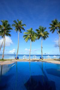 a swimming pool with palm trees and the ocean at Palau Pacific Resort in Koror