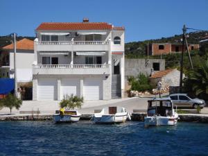 three boats in the water in front of a house at Apartments Mirko in Vinišće