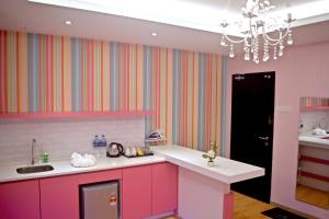 a kitchen with pink cabinets and a sink and a chandelier at Iconic Suites & Pods Hotel in Ipoh