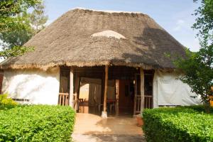 a hut with a thatched roof with a patio at Hotel Nok Continental in Gulu