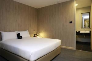 a bedroom with a large white bed and a bathroom at Sleep Box by Miracle -Booked on Hourly Basis in Bangkok