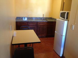 a kitchen with a refrigerator and a table and a microwave at Mesa Oasis Inn & Motel in Mesa