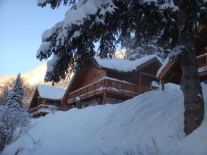 une cabane en rondins dans la neige avec un arbre dans l'établissement Chalet Clementine, à Oz