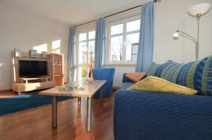 ein Wohnzimmer mit einem blauen Sofa und einem Tisch in der Unterkunft Villa Seerose - Appartement 01 in Ostseebad Sellin