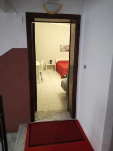 una puerta que conduce a un dormitorio con cama roja en XXI Agosto Home, en Reggio Calabria