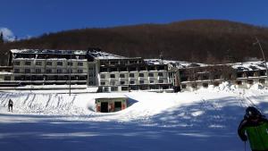 a large building in the snow with a skier in front at Val di Luce-Foemina 78 in Abetone