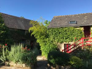 an ivy covered house with a red gate and a garden at Le Châtel in Riec-sur-Bélon