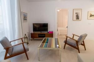 sala de estar con mesa, 2 sillas y TV en Apartamento Rosario 49 en Cádiz