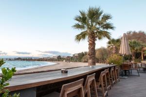 a long wooden bar with chairs and a palm tree at Krystal Apartment in Athens