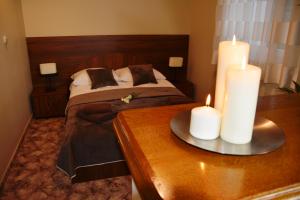 a bedroom with a bed with two candles on a table at Hotel Irena in Morąg