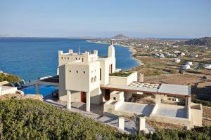 un edificio blanco en la cima de una colina junto al océano en Villa Paradise in Naxos en Plaka