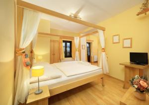 sypialnia z łóżkiem z baldachimem i telewizorem w obiekcie Hotel Garni Myší Díra w Czeskim Krumlovie
