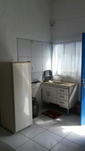 a small kitchen with a refrigerator and a sink at Apartamentos Águia Suíte casal 2 in Ilha Comprida