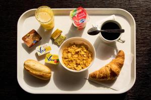 uma bandeja com comida para o pequeno-almoço e uma chávena de café e croissants em Résidence Internationale De Paris em Paris