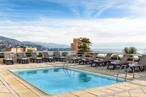 a swimming pool on the roof of a building with chairs and a view at Aparthotel Adagio Monaco Palais Joséphine in Beausoleil