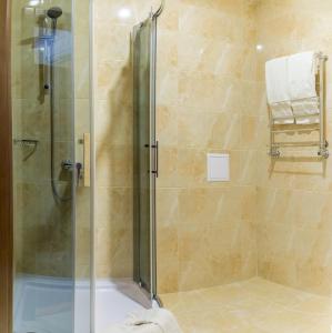 uma casa de banho com um chuveiro e uma porta de vidro em Hotel Patriarshyi em Lviv