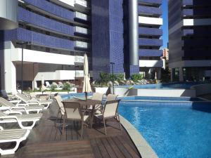 a patio with a table and chairs next to a pool at Apartamento Em Fortaleza De Frente Para O Mar in Fortaleza