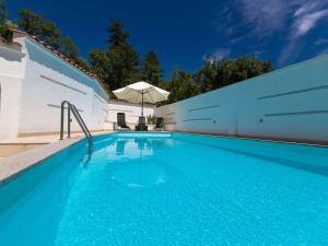 a swimming pool with blue water and an umbrella at Apartment Villa Zdenka in Crikvenica