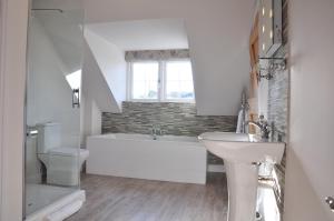 a white bathroom with a tub and a sink at Rosebank Barn in Brentor