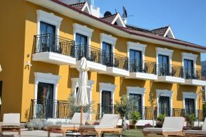 a yellow building with chairs and an umbrella at Michelangelo Boutique Hotel Dalyan in Dalyan