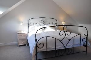 a bedroom with a black metal bed with white sheets at Rosebank Barn in Brentor