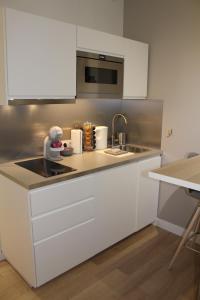 a kitchen with white cabinets and a sink at LOCKIA APPART-HÔTELS AUTOMATIQUES - Nantes Centre in Nantes