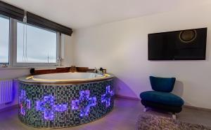 ein Badezimmer mit einer Badewanne, einem Stuhl und einem TV in der Unterkunft June street Spa apartments in Vilnius