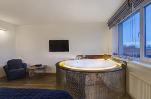 bagno con vasca, TV e sedia di June street Spa apartments a Vilnius Altre 7 foto