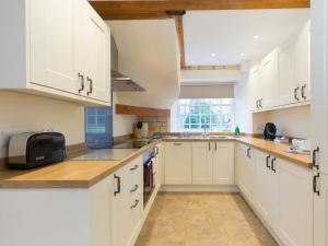 a white kitchen with white cabinets and a microwave at Charles I in Winchcombe