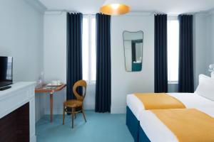 a bedroom with a bed and a television at Hôtel Céleste Batignolles Montmartre in Paris