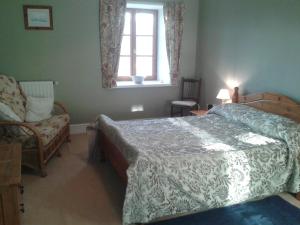 a bedroom with a bed and a chair and a window at Chez Valade in Payroux