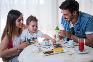 Un uomo e una donna seduti a un tavolo con un bambino di Hotel Doge ad Alba Adriatica