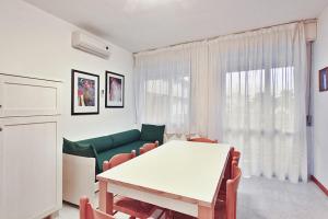 un soggiorno con tavolo bianco e divano verde di Condominio Casamare a Lignano Sabbiadoro