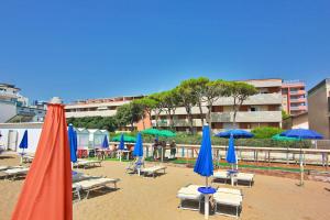 una spiaggia con ombrelloni, sedie a sdraio e tavoli di Condominio Casamare a Lignano Sabbiadoro