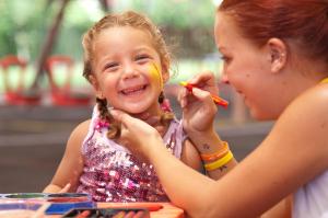Una joven sonríe mientras una mujer se cepilla los dientes. en Marvida Family Eco - All Inclusive & Kids Concept, en Side