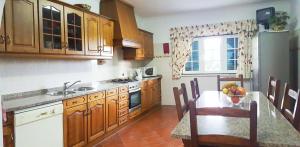 a kitchen with wooden cabinets and a table with a bowl of fruit at Quinta Do Ribeirinho in Vilar da Mó